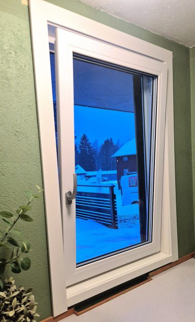 Fönster med snölandskap och grön vägg inomhus.