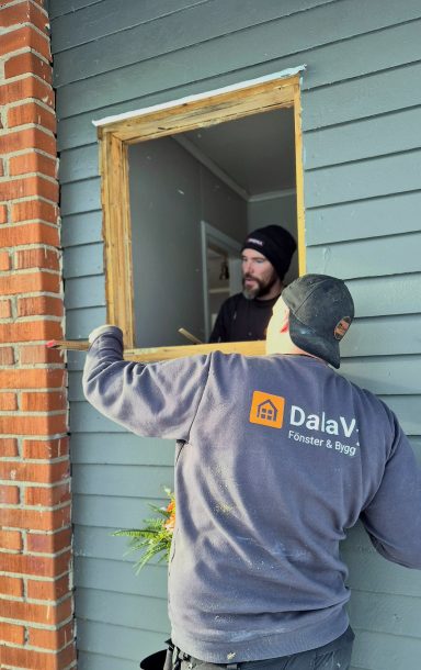 Två män arbetar med att installera ett fönster i en väggöppning.